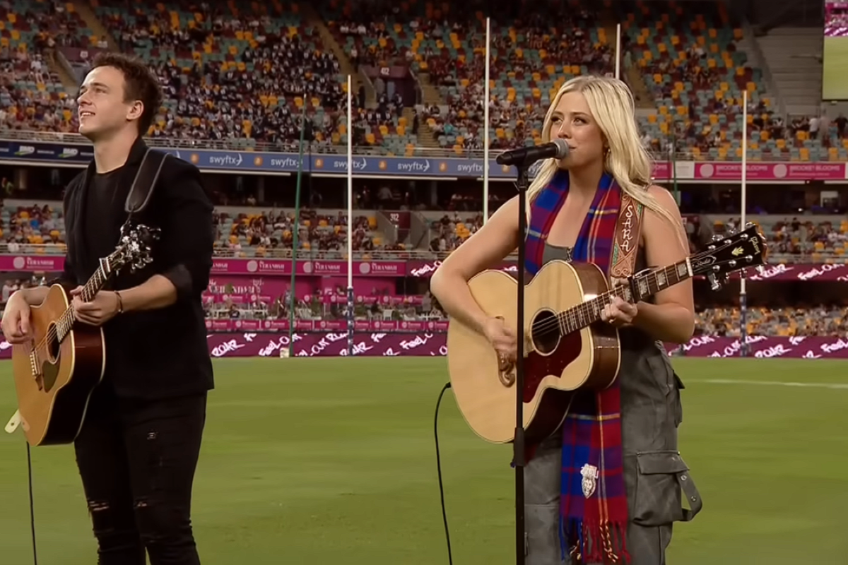 Sara Berki singing and playing guitar in a stadium