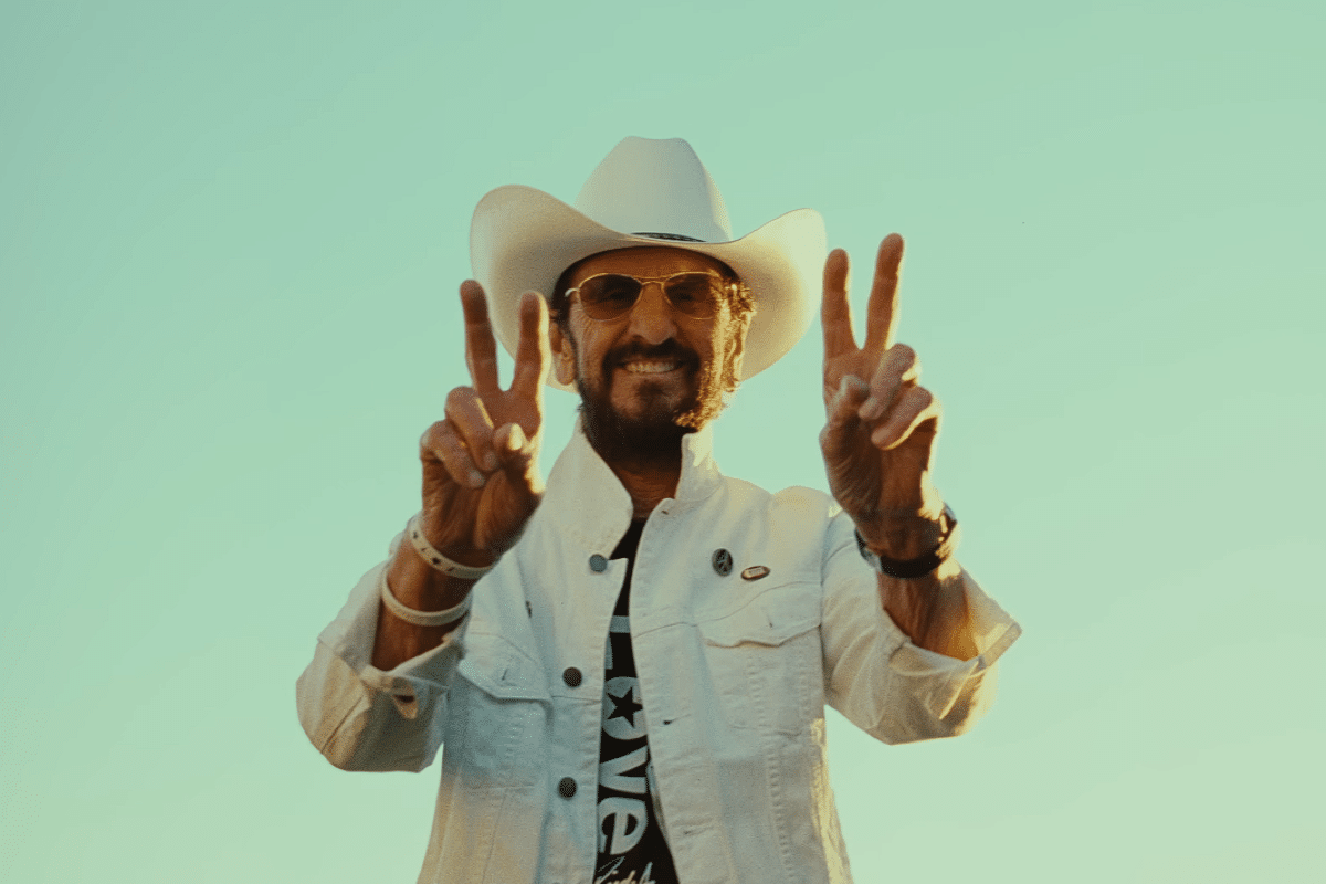 Ringo Starr with a cowboy hat on holding up the peace sign